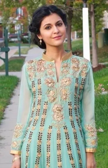 Kulsoom outdoors, in an embroidered teal dress.
